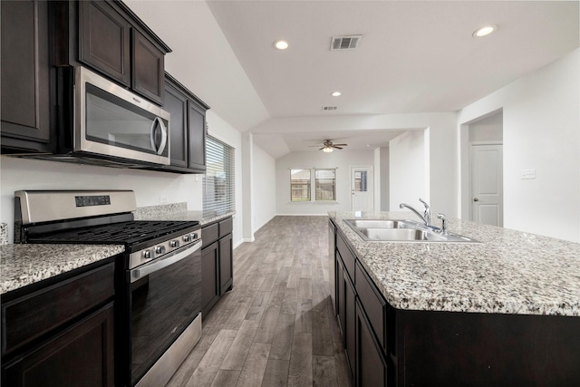 kitchen with appliances with stainless steel finishes, sink, light wood-type flooring, ceiling fan, and an island with sink