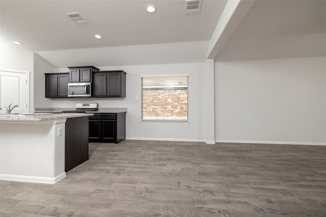 kitchen featuring lofted ceiling, light hardwood / wood-style floors, light stone counters, and white range