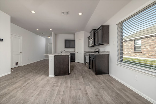 kitchen with a kitchen island with sink, light wood-type flooring, and stainless steel appliances