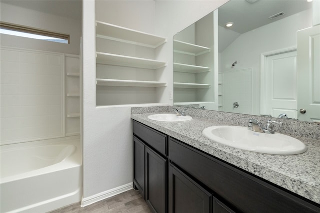 bathroom with wood-type flooring, vanity,  shower combination, and vaulted ceiling