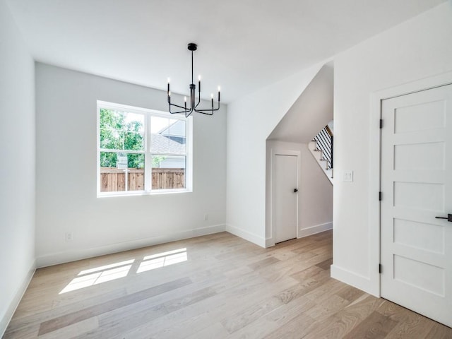 unfurnished dining area featuring light hardwood / wood-style flooring and an inviting chandelier