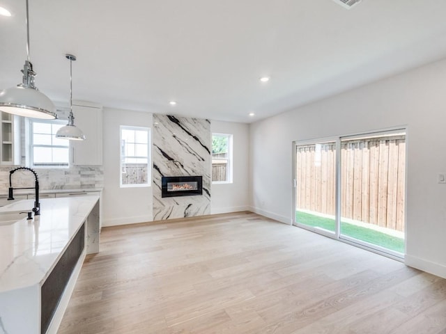 kitchen featuring a premium fireplace, light stone countertops, plenty of natural light, and pendant lighting