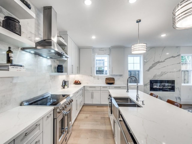 kitchen with white cabinets, pendant lighting, wall chimney exhaust hood, and sink