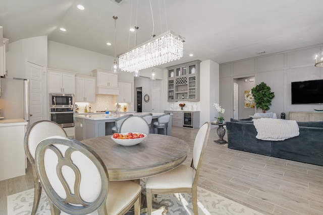 dining space with light hardwood / wood-style floors, beverage cooler, and a chandelier