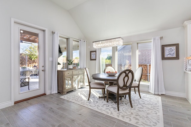 dining area with an inviting chandelier, light hardwood / wood-style floors, and vaulted ceiling