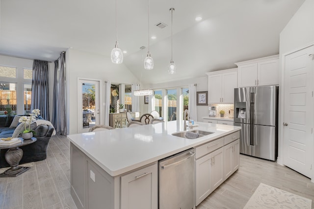 kitchen featuring white cabinets, stainless steel appliances, a center island with sink, and sink