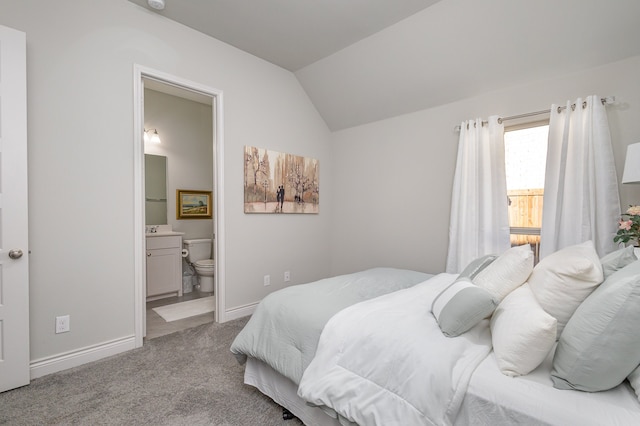 carpeted bedroom with connected bathroom, vaulted ceiling, and sink