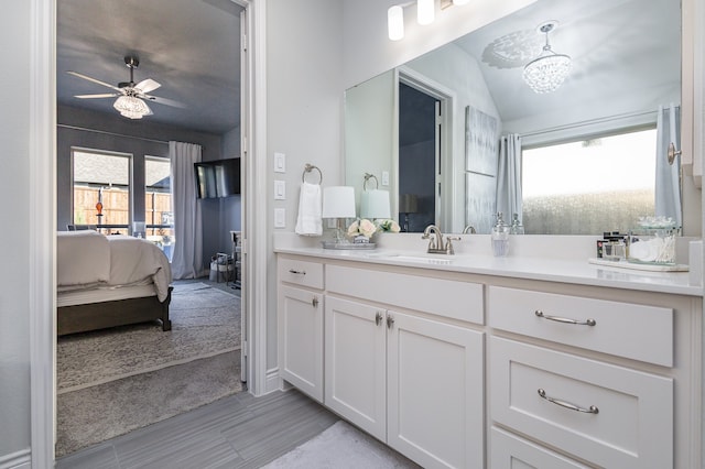 bathroom with ceiling fan with notable chandelier, lofted ceiling, and vanity