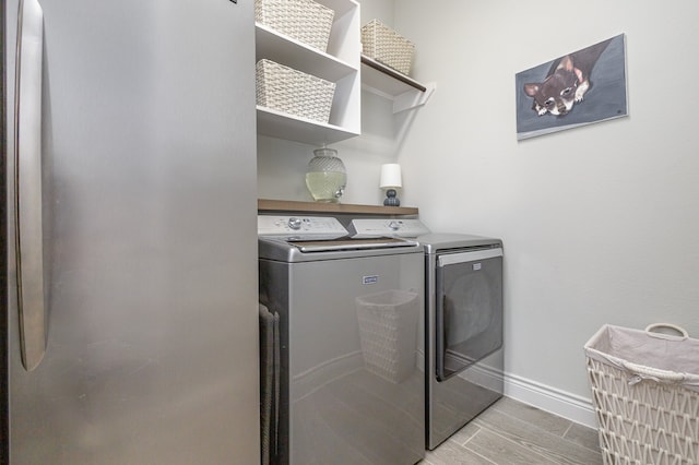 laundry room with washing machine and dryer and light hardwood / wood-style floors