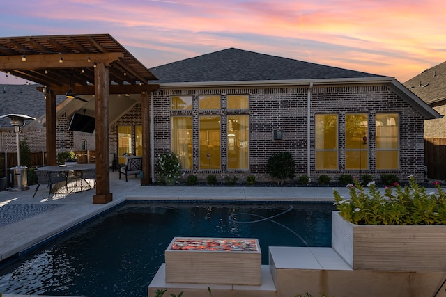 back house at dusk featuring a pergola and a patio