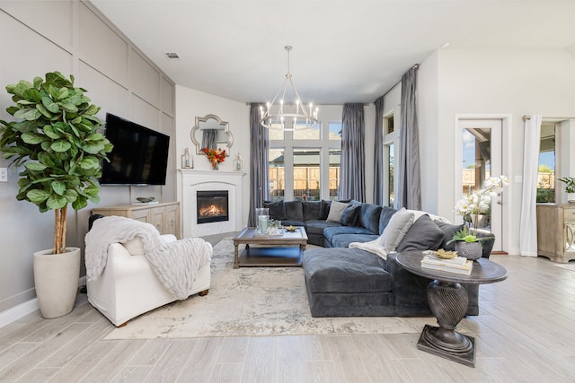 living room with an inviting chandelier, a healthy amount of sunlight, and light wood-type flooring