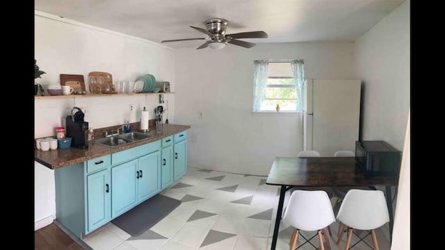 kitchen featuring a kitchen breakfast bar, white refrigerator, sink, ceiling fan, and blue cabinetry