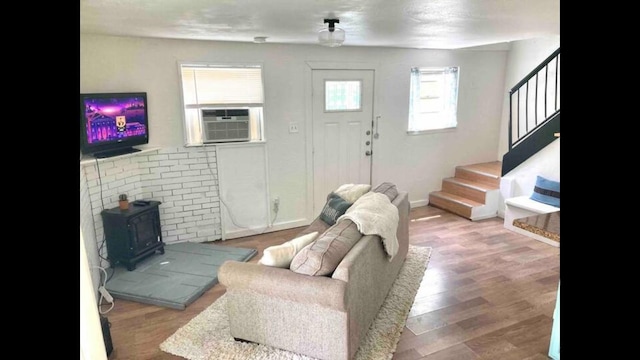 living room with hardwood / wood-style flooring, a wood stove, and cooling unit