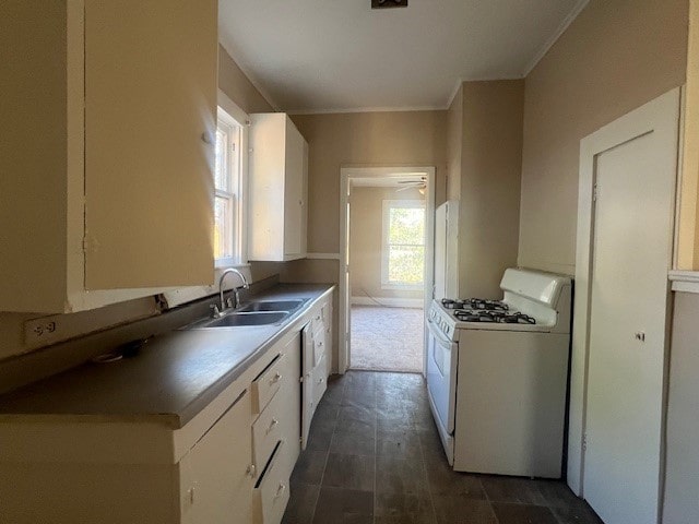 kitchen featuring sink, white range with gas stovetop, and white cabinets