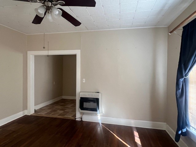 unfurnished living room featuring hardwood / wood-style floors, heating unit, ceiling fan, and ornamental molding