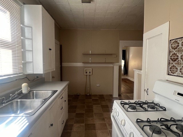 kitchen with white range with gas cooktop, sink, and white cabinetry