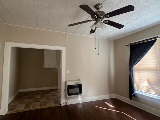 unfurnished room with ceiling fan, heating unit, and dark hardwood / wood-style flooring