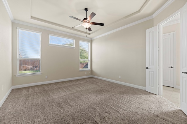 carpeted empty room with a raised ceiling, crown molding, and ceiling fan