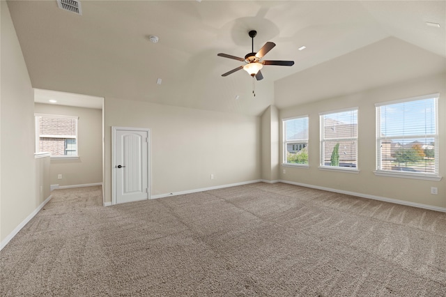 empty room featuring light colored carpet, vaulted ceiling, and plenty of natural light