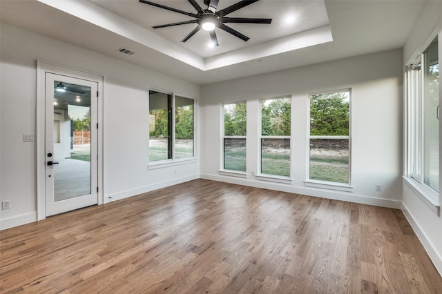 unfurnished sunroom with ceiling fan and a raised ceiling