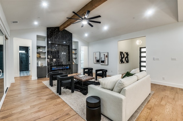 living room with a fireplace, vaulted ceiling with beams, light hardwood / wood-style flooring, and ceiling fan