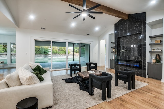 living room featuring lofted ceiling with beams, ceiling fan, wood-type flooring, and a tile fireplace