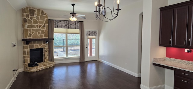 unfurnished living room with lofted ceiling, dark hardwood / wood-style flooring, ceiling fan with notable chandelier, and a stone fireplace