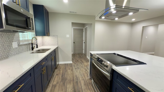 kitchen with stainless steel appliances, sink, light stone counters, dark hardwood / wood-style floors, and blue cabinets