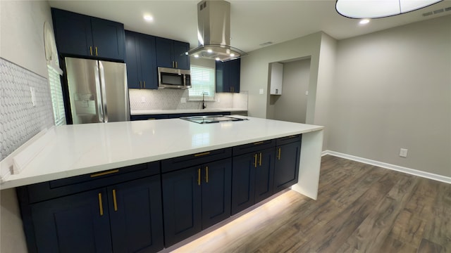 kitchen with island range hood, blue cabinetry, dark hardwood / wood-style floors, light stone countertops, and appliances with stainless steel finishes