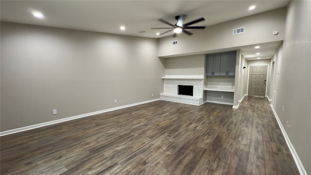 unfurnished living room featuring a brick fireplace, ceiling fan, and dark hardwood / wood-style flooring