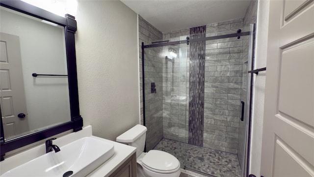 bathroom with toilet, vanity, and a shower with shower door