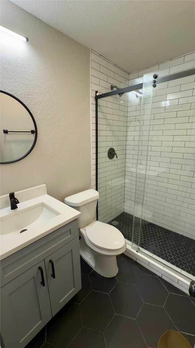 bathroom with toilet, a shower with door, tile patterned flooring, a textured ceiling, and vanity