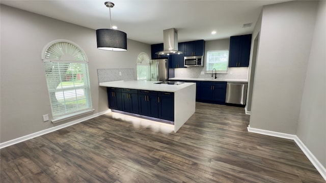 kitchen with stainless steel appliances, kitchen peninsula, dark hardwood / wood-style floors, blue cabinetry, and wall chimney range hood