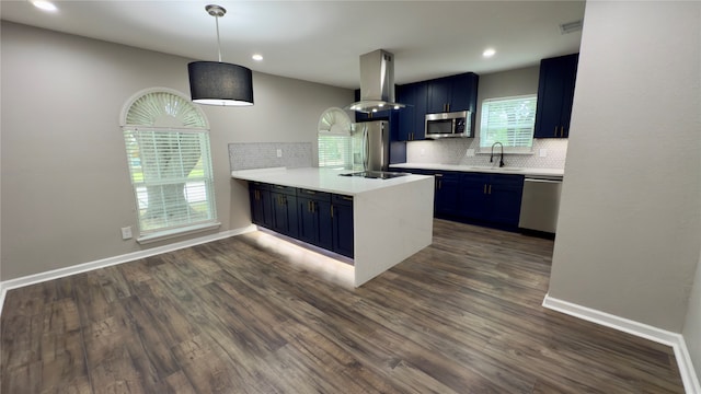 kitchen featuring kitchen peninsula, appliances with stainless steel finishes, wall chimney exhaust hood, and blue cabinets