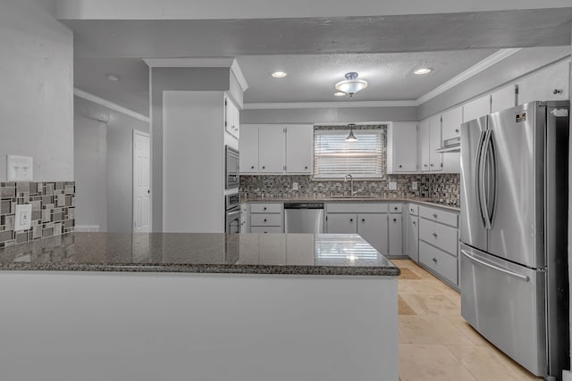 kitchen featuring appliances with stainless steel finishes, sink, white cabinets, dark stone countertops, and kitchen peninsula