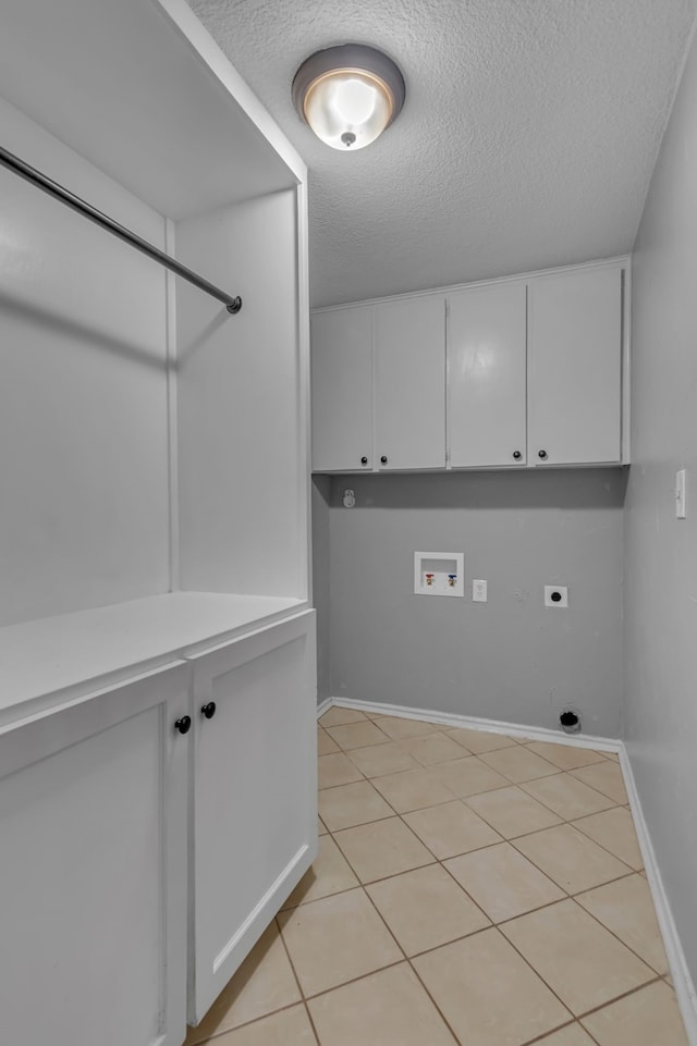 clothes washing area featuring cabinets, washer hookup, a textured ceiling, light tile patterned floors, and hookup for an electric dryer