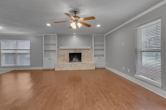 unfurnished living room featuring a fireplace, wood-type flooring, ceiling fan, and crown molding