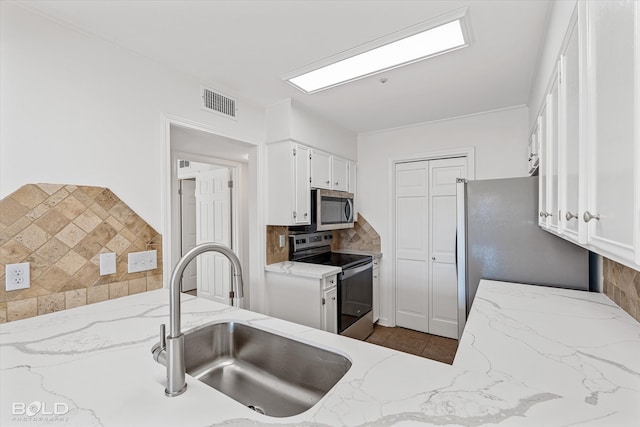 kitchen featuring stainless steel appliances, sink, light stone counters, backsplash, and white cabinets