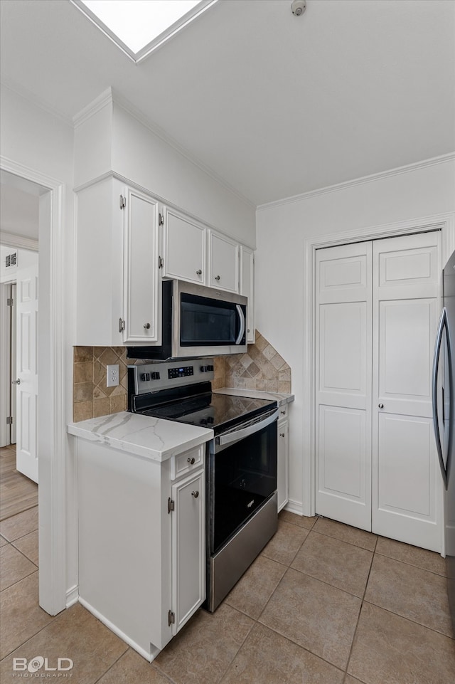 kitchen with light tile patterned floors, backsplash, light stone countertops, white cabinetry, and appliances with stainless steel finishes