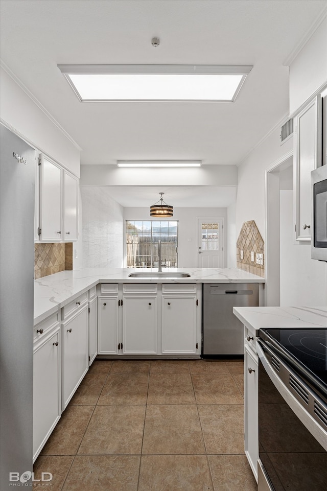 kitchen featuring tasteful backsplash, light tile patterned flooring, stainless steel appliances, sink, and white cabinets