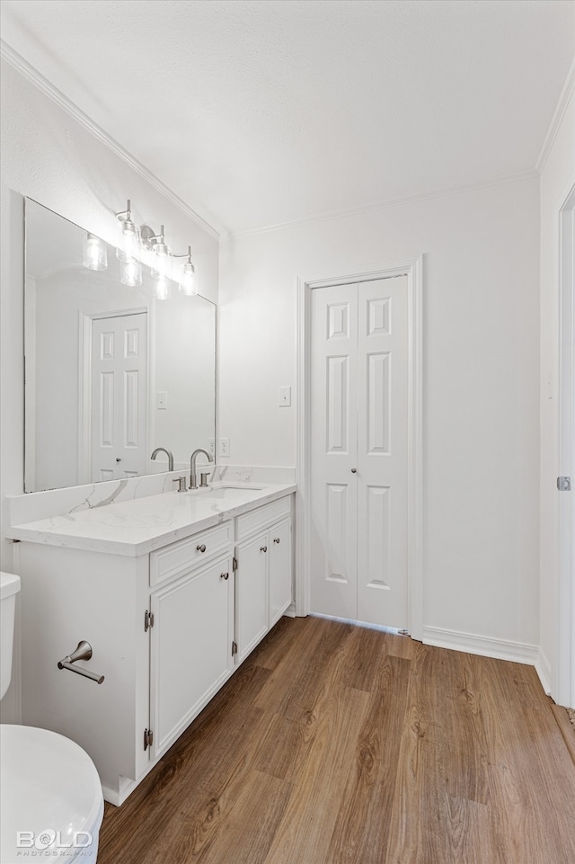 bathroom with crown molding, vanity, hardwood / wood-style flooring, and toilet