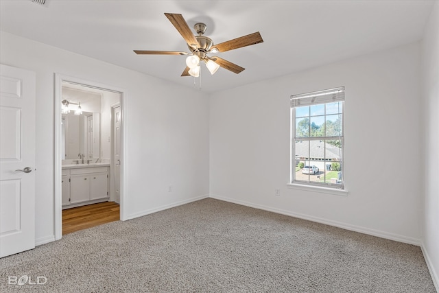 unfurnished bedroom with ensuite bathroom, ceiling fan, sink, and carpet