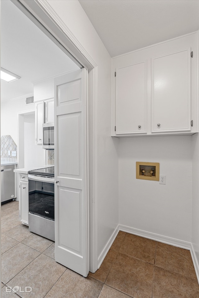 kitchen with white cabinets, light tile patterned floors, and appliances with stainless steel finishes