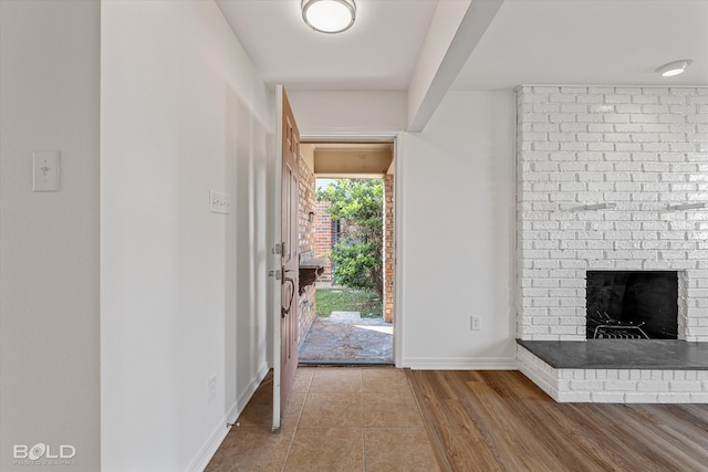 foyer entrance with a brick fireplace and wood-type flooring