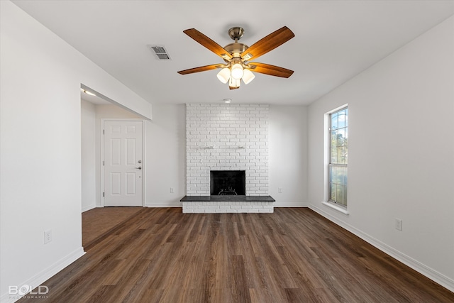 unfurnished living room with ceiling fan, dark hardwood / wood-style floors, and a brick fireplace