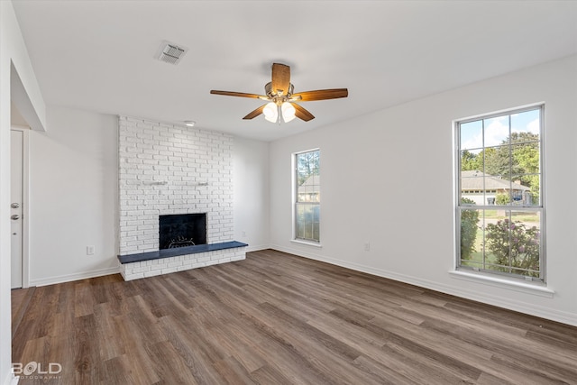 unfurnished living room with a brick fireplace, dark hardwood / wood-style floors, and plenty of natural light