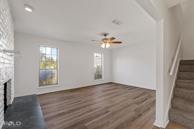 unfurnished living room with hardwood / wood-style flooring, ceiling fan, and a brick fireplace