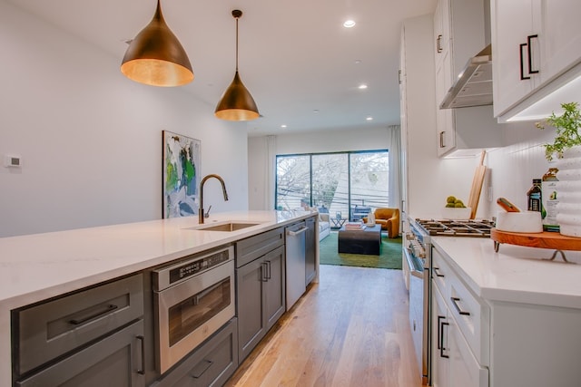 kitchen with stainless steel appliances, hanging light fixtures, gray cabinetry, and light stone counters