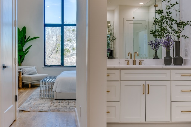 bathroom with a shower with shower door, vanity, and wood-type flooring