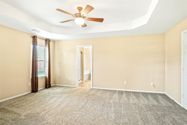 carpeted spare room featuring ceiling fan and a raised ceiling